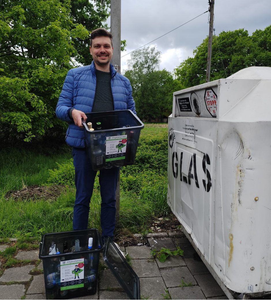 Altglashelden-Gründer Henning Lemke mit Altglasbox neben einem Glascontainer